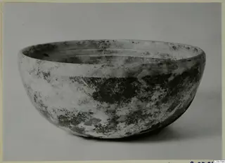 Cast glass bowl with a thick, rounded wall and a weathered, mottled surface