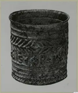 Cylindrical vessel with raised chevron band and rounded motifs, shown against a plain grey backdrop