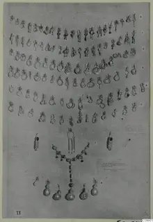 Rows of gold earrings and a bead necklace with pendants laid out on grey cloth, in numbered rows