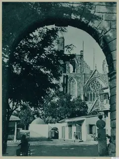 Through a stone archway, the ruined facade of St Nicholas Cathedral in Famagusta, with trees and buildings in front