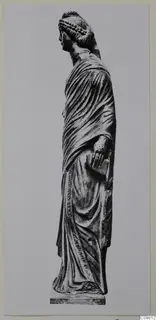 Standing draped stone statue, seen in profile facing left, on a rectangular base