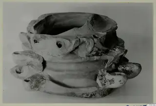 Terracotta lamp with a wide open top and several rounded projecting nozzles, some with holes.