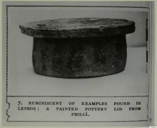 Pottery lid with a broad flat top over a cylindrical body, shown in a photo mount with a printed caption