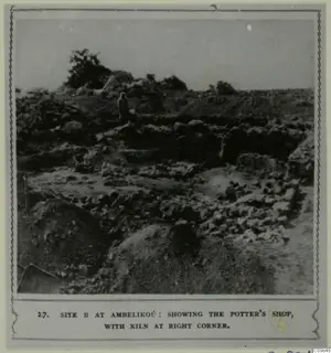 Excavated area of low stone walls and rubble with one standing person on a raised bank