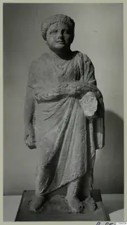 Standing limestone statue of a draped figure from Mersinaki, photographed against a grey backdrop