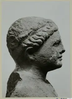 Carved stone head in profile from Mersinaki, facing right, with wavy hair drawn back over the ear.