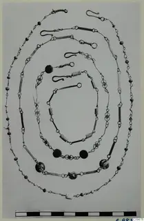 Several nested chains and necklaces of wire links, beads and tubular segments, laid out in oval loops on a plain background.