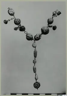 Necklace of glass and stone beads and metal chain, laid out in a V shape.