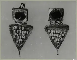 Pair of jewellery pieces: square plates with dark centres above triangular frames holding pale beads, on a grey background.