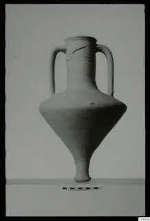 Two-handled jar with a narrow neck and tapering foot, shown on a pale surface beside a measuring scale.
