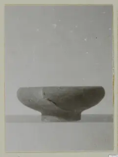 Bowl with a low ring base and a crack running down one side, shown in side view on a plain surface