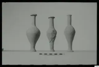 Three narrow-necked pottery vessels with bulbous bodies and flat bases, standing in a row on a plain surface.