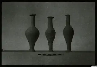 Three tall narrow-necked pottery vessels standing in a row with a scale bar in front.