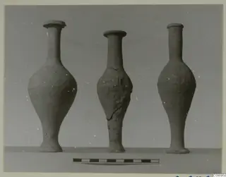 Three pottery jars with long necks standing in a row, with a scale bar in front