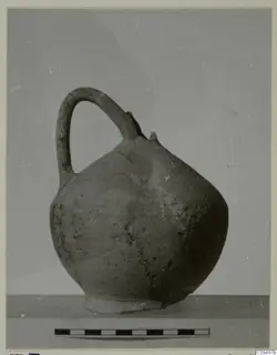 Round-bodied jug with a strap handle and pinched spout, shown with a scale bar beneath it