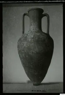 Two-handled vessel with a tall neck and tapering body, photographed upright with a scale bar beside it