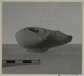 Clay oil lamp with a pointed nozzle to the right, shown beside a scale bar