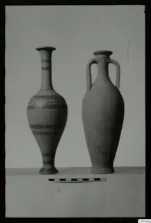 Two vessels on a shelf with a scale bar: a tall narrow-necked vessel with painted bands and a two-handled jar with a plain body.