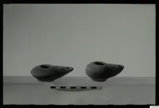 Two lamps with filling holes and pinched nozzles, standing side by side with a scale bar in front of them.