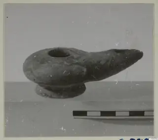 Clay oil lamp with a round filling hole and long pointed spout, shown beside a scale bar