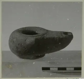 Clay lamp with a round filling hole and pinched spout, shown in side view beside a scale bar.