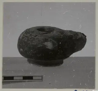 Dark pottery vessel with a wide top opening, a pinched spout and a ring foot, shown with a scale bar