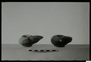 Two pottery oil lamps with spouts, with a scale bar in front of them