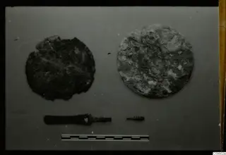 Finds from Ajii Omologitades, Politiko T1914 and Limassol Oasis T1: two corroded metal discs and two rods with a scale bar.