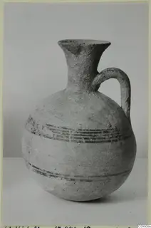 Pottery White Painted II jug with a flaring neck, single handle and dark painted bands on the body