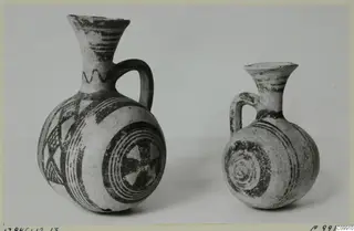 Jug and juglet side by side, decorated with dark painted bands, concentric circles and triangles.