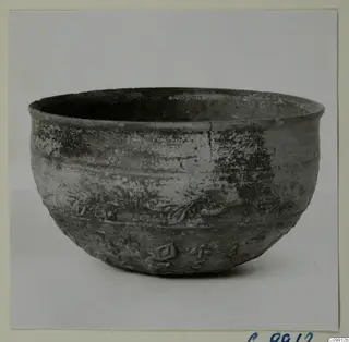 Grey-black pottery bowl with a wide mouth and relief decoration of bands and motifs on its body
