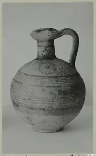 Round-bodied jug with a trefoil-like mouth and strap handle, painted with horizontal bands and a circular motif.