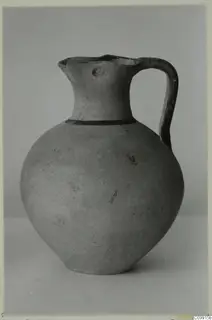 Pottery White Painted III-1 jug with a round body, a dark band at the neck and a strap handle