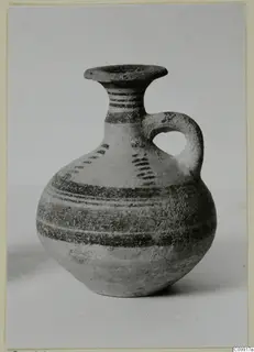 Pottery Bichrome IV jug with a single loop handle and dark painted bands, standing on a plain background