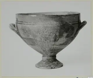 Footed bowl with two horizontal handles and concentric circle motifs painted on its body.