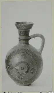 Painted pottery jug with a ribbed flared neck, loop handle and concentric circle decoration on the body