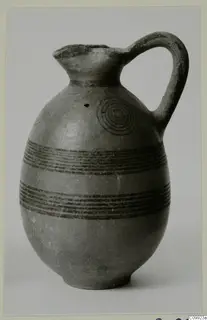 Juglet with dark painted bands and concentric circles on its body, photographed against a plain background