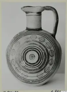 Jug with a tall neck, strap handle and concentric circle decoration painted in dark bands on its rounded body