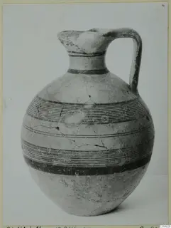 Single-handled jug with a pinched mouth and horizontal bands of dark paint on its body and neck