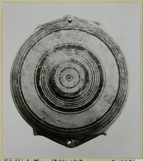 Pottery Bichrome IV plate with concentric painted rings and two small pierced lugs, seen from above