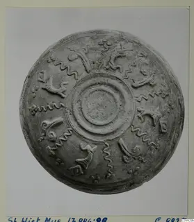 Shallow bowl seen from above, with raised concentric rings at the centre and relief motifs around the body