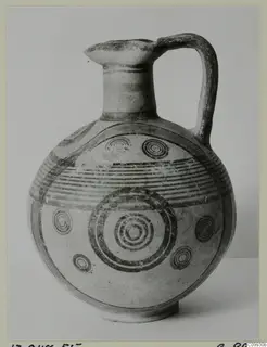 Round-bodied jug with a high loop handle and concentric circle and banded painted decoration in dark paint.