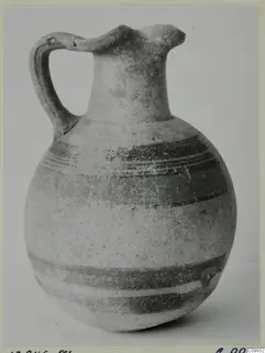 Bichrome IV jug with a handle and trefoil-like spout, decorated with dark painted bands on a pale body.