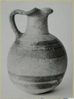 Bichrome V jug with a round body, long neck, strap handle and dark painted bands