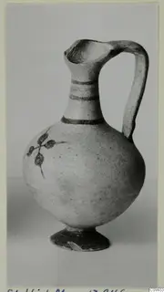 Bichrome IV jug with a round body, tall strap handle, painted neck bands and a leafy stem motif on the body