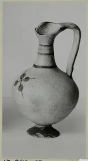 Pottery Bichrome IV jug with dark painted bands on the neck and a painted leaf sprig on the body