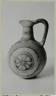 Round-bodied jug with a loop handle, painted with concentric bands and a central spoked wheel motif