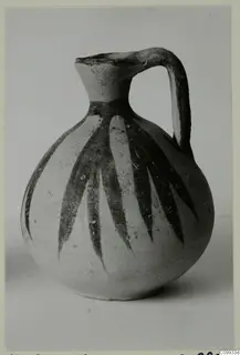 Round-bodied jug with a tall flaring neck and strap handle, decorated with dark vertical leaf-like bands.