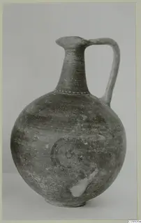 Globular jug with a tall neck and strap handle, decorated with concentric circles and a band of dots at the neck