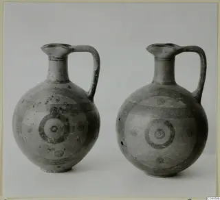 Two painted pottery jugs with single loop handles, decorated with black concentric circles and bands